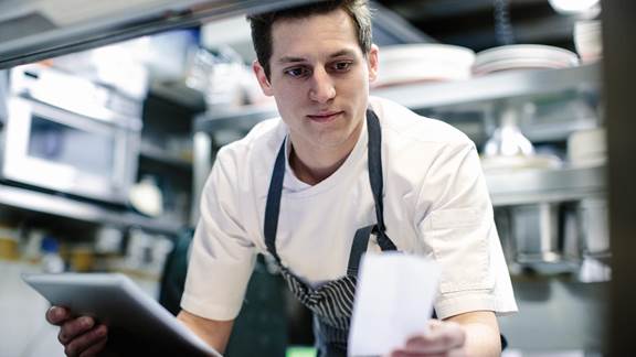 Gordon Food Service - chef checking a paper order versus tablet